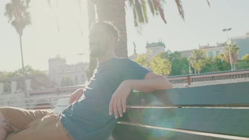 Man Relaxing on Park Bench in Sunny City
