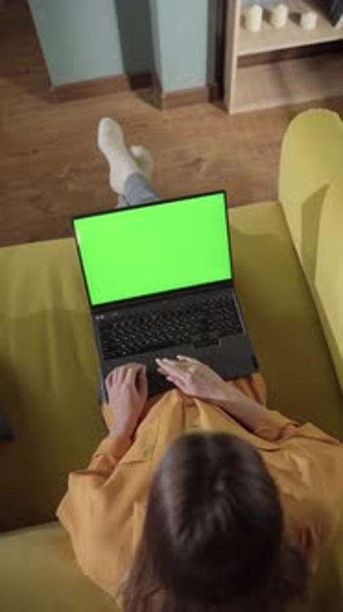 Woman Relaxing on a Yellow Sofa Wearing a Yellow Shirt and Socks Working or Studying From Home Using