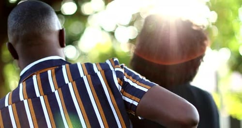 African man putting arm around lover outside at park