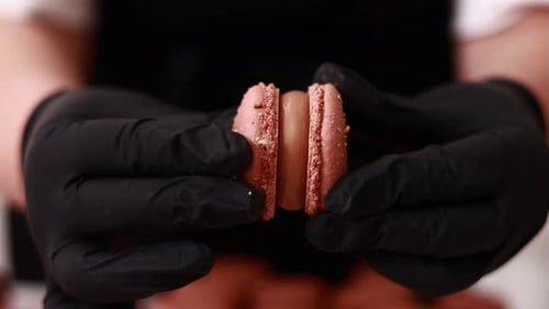 Hands Assembling Pink Macarons with Cream Filling