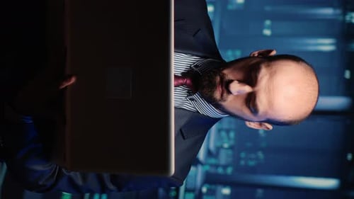 Man in Suit Holding Laptop at Night