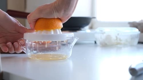 manos de mujer exprimiendo naranja para hacer jugo