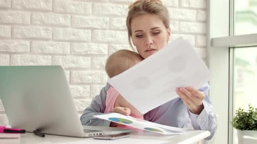 Business Mother Working From Home. Mom Holding Baby Girl at Workplace In