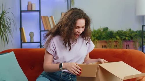 Happy Young Woman Shopper Unpacking Cardboard Box Delivery Parcel Online Shopping Purchase at Home