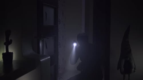 Shadowy Figure Exploring Dark Room with Flashlight