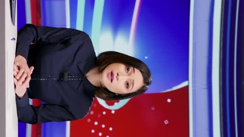 Woman Speaking at Desk in Broadcast Studio Vertical