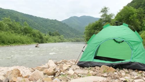 Ein wunderschöner Blick auf die Berge, einen Gebirgsfluss, neben dem sich ein grünes Zelt befindet.