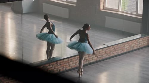 Elegant Ballerina Spins Against Mirror in Dance Studio