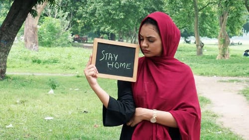 Young Adult Holding Stay Home Sign in Park