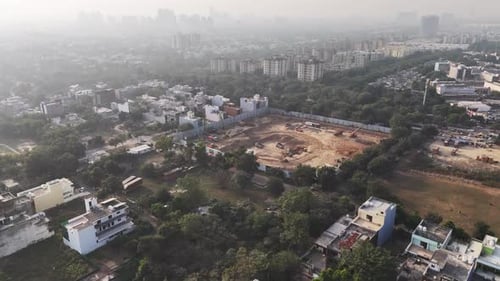 Imágenes aéreas de un sitio de construcción activo con excavadoras, volquetes y movimiento de tierras