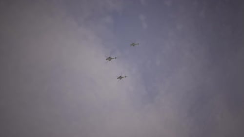 Military Helicopters Flying in Formation Across Cloudy Sky