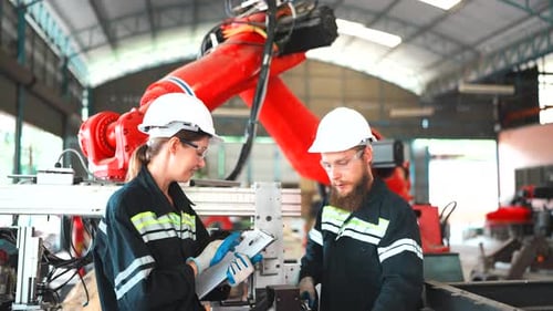 Una ingeniera especialista y un técnico de mantenimiento inspeccionan los componentes del brazo del robot.