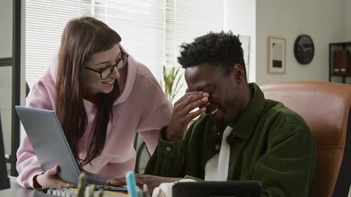 Fröhliche, vielfältige Programmierer diskutieren über das Skript für ein Projekt auf dem Laptop