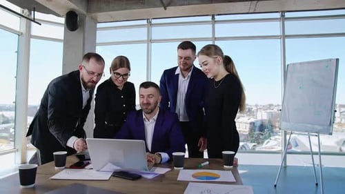 Jovens colegas de trabalho positivos discutindo ideias no escritório. Homem no centro digitando no computador
