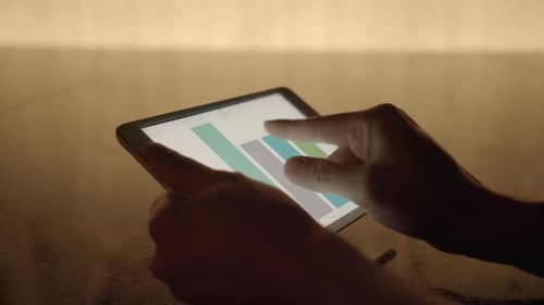Hands Using Touchscreen Tablet with Charts and Graphs