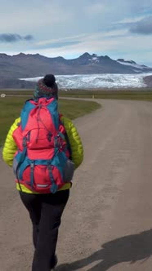 Woman Hiking on Dirt Road Towards Snowy Mountains