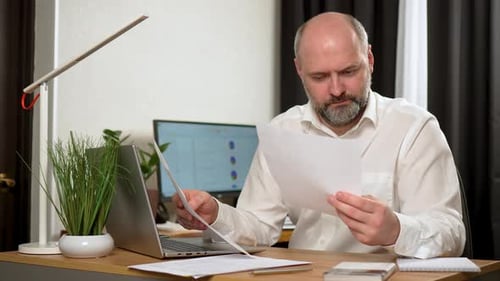 Man Reviews Documents at His Office Desk