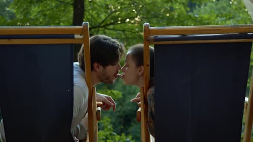 Young Couple Touch Noses in Outdoor Chairs