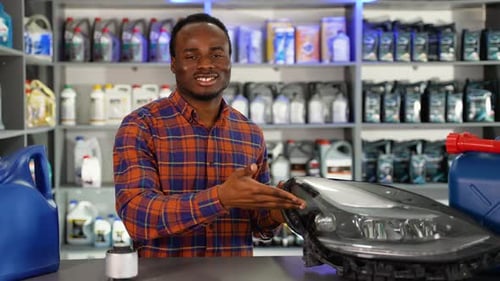 Portrait of Black Salesman with Automotive Headlight in Auto Parts Store