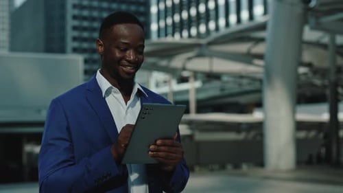 Portrait of African American Man Uses Tablet Walking Along in Urban Street