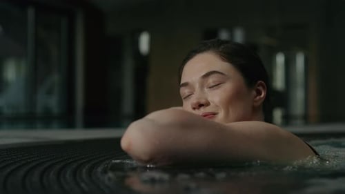 Niña disfruta relajándose en el jacuzzi Niña sonriente cierra los ojos