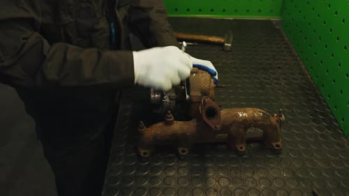 Worker disassembles for repair old rusty car turbine turbocharger