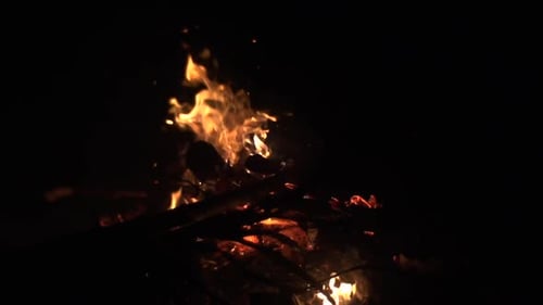 Des flammes ardentes s'élevant et brûlant intensément au-dessus d'un feu de bois filmé au ralenti
