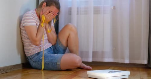 Woman Crying on Floor with Measuring Tape