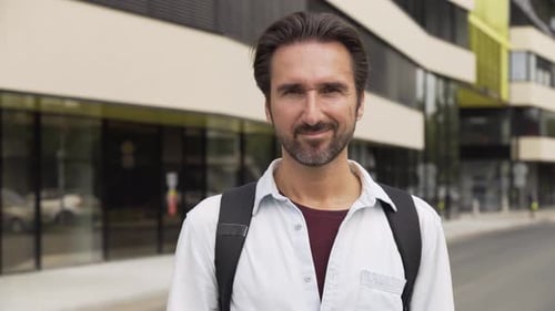 A Handsome Caucasian Man Shows a Thumb Up to the Camera with a Smile in a Street in an Urban Area