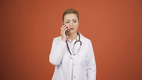 Woman Doctor Talking on Mobile Phone, Orange Background
