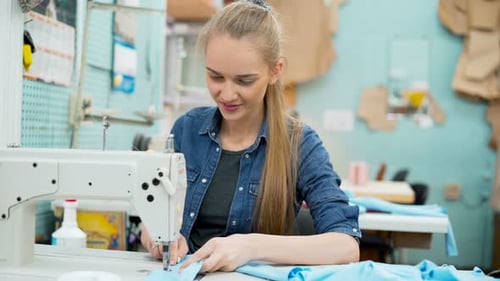 Dressmaker Working on a Sewing Machine in Her Studio at Table. Professional