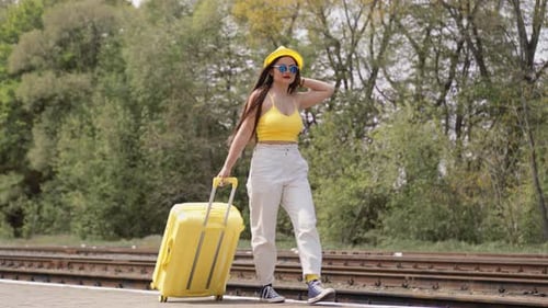 Stylish Woman Walking with Yellow Suitcase at Train Station
