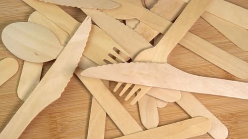 La
vajilla desechable ecológica de madera gira sobre la mesa de madera. Pila de cucharas de madera, tenedores