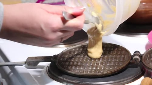 A Woman Puts Dough On A Hot Waffle Iron. Preparing Waffle Cones. Shot Close Up