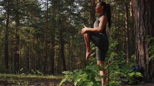 Woman Stretching On Yoga Mat In Forest