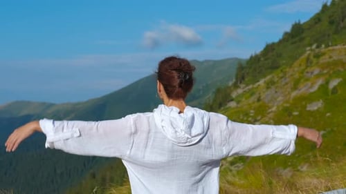 Woman Reaching Arms in Mountainous Landscape