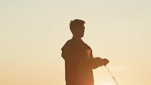 Boy Juggling with Fire Chains at Sunset