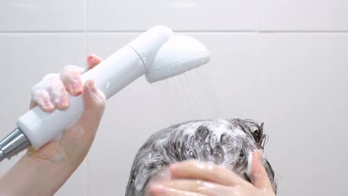 Woman Washing Brown Hair with Shower Head Close Up