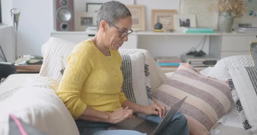 Focused Woman Working on Laptop at Home on Sofa