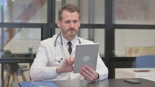 Middle Aged Doctor Using Tablet in Clinic