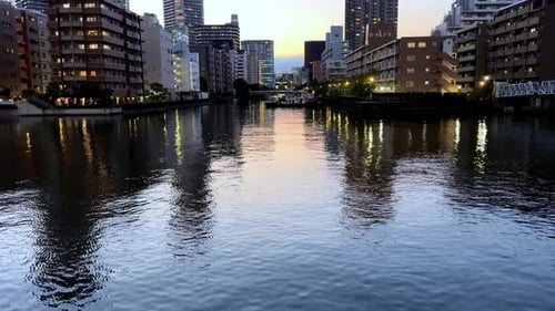 Reflections of city lights on calm water at dusk
