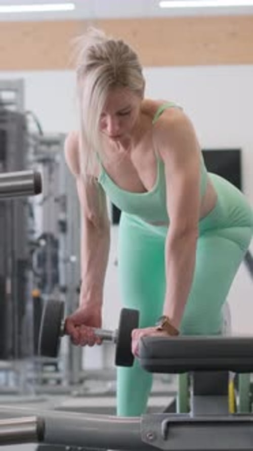 Woman Dedicated to Fitness Lifting Weights at Gym