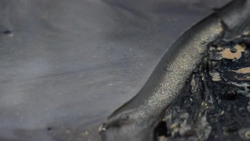 Gros plan de motifs d'encre tourbillonnants dans l'eau, créant une texture abstraite fascinante