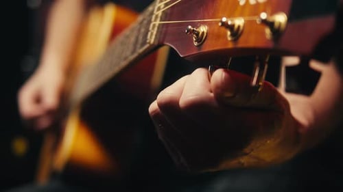 Young Musican Man Checking Strings of Acoustic Guitar Closeup Male Guitarist Tuning Sound of Musical
