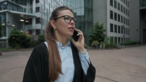 Businesswoman in City Street Walking to Office Tower and Talking on the Phone