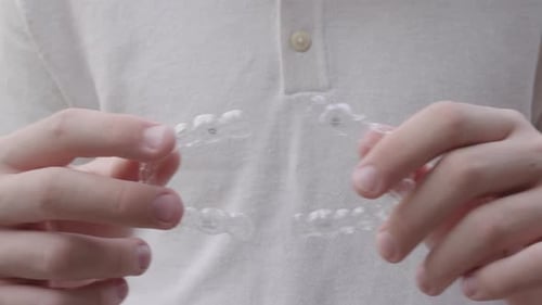 Man holding clear plastic dental aligners for teeth