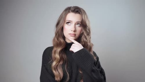 Une fille perplexe est dans le doute, planifiant mentalement quelque chose en utilisant la pensée critique.