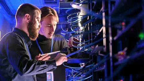 Two men analysing servers in a data centre