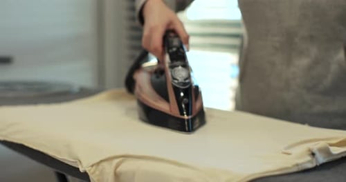 Woman Using Iron with Steam Mode for Clothes Home Routine Housekeeping