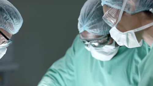 Diverse surgeons with face masks during surgery in operating room in slow motion